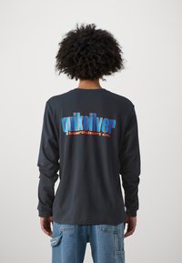 Sort langærmet skjorte med et flerfarvet "Quiksilver boardshort co." logo på ryggen. Casual pasform med ribbede mansjetter.