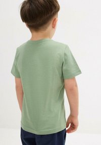 T-shirt verde in cotone con colletto rotondo classico e maniche corte, caratterizzato da un design semplice e una consistenza morbida.