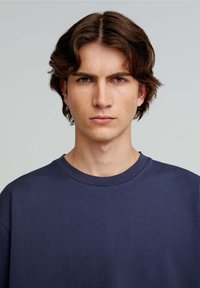 Marineblå bomulds t-shirt med rund hals, korte ærmer og en glat tekstur, der har minimale syninger.