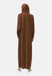 Lang brun kjole lavet af letvægtsmateriale med lange ærmer, en løs pasform, og en matchende hijab draperet over skulderen.