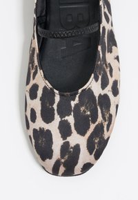 Bailarinas con un estampado de leopardo en tonos marrones y negros, que presentan una banda elástica negra y una parte superior de tela suave.