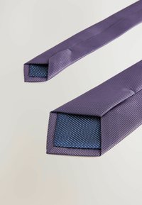 Cravat texturat violet cu căptușeală solidă albastră, prezentând buline albe, capete înguste și o finisare netedă.