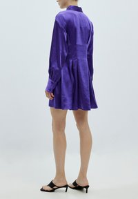 Lila Satinhemdkleid mit langen Ärmeln, geknöpften Manschetten, tailliertem Oberteil und ausgestelltem Rock. Glatte Textur und Kragendetails.