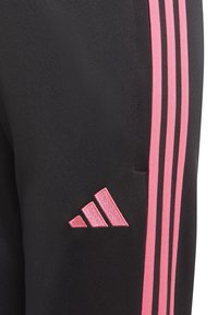 Schwarze Sporthosen mit pinkem Dreistrichdesign, mit einem kleinen pinken gestickten Logo auf der linken Seite. Hergestellt aus glattem, dehnbarem Stoff.