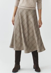 Brauner Karo-Rock mit ausgestellter Silhouette, der diagonale Linien und eine weiche Textur aufweist. Kombiniert mit knielangen braunen Wildleder-Stiefeln.