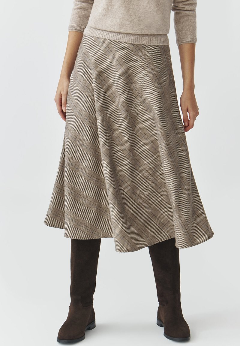Brauner Karo-Rock mit ausgestellter Silhouette, der diagonale Linien und eine weiche Textur aufweist. Kombiniert mit knielangen braunen Wildleder-Stiefeln.