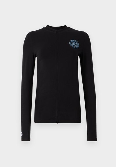 Casaco preto de manga longa com fecho de correr, apresentando um logótipo azul em forma circular no lado esquerdo do peito e um design ajustado com costuras planas.