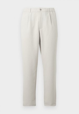 Calças bege claro de corte descontraído com ligeiro brilho, apresentando um cós elástico, bolsos frontais e um design de perna afunilada.