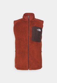 Chaleco de forro polar rojo con cuello alto, cierre de cremallera y un bolsillo en el pecho negro con un logo. Textura suave y diseño sin mangas.