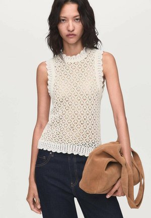 Top tank in cotone bianco all'uncinetto con bordi a scallop e design a maglia aperta, abbinato a jeans in denim scuro e una borsa in suede color tan.