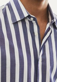Camicia a bottoni a righe in viola e bianco, con colletto classico, trama liscia e righe verticali regolarmente distanziate.