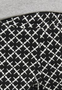 Svarta leggings med vitt geometriskt mönster, med en elastisk midja och en strukturerad tyg.