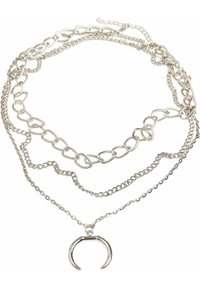 Collier argenté à plusieurs couches avec différents styles de chaînes, y compris des chaînes liées et délicates, portant un pendentif en forme de U.