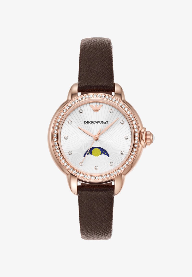 Roséguld klocka med kristall bezel, vit urtavla, brun strukturerad läderrem, diamanter som timmarkörer och sol-månfaser indikator vid 6-tiden.