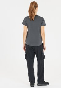 Grå kortärmad t-shirt med rund hals, kombinerad med löst sittande svarta cargobyxor med sidofickor och en avslappnad silhuett.