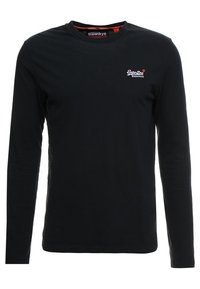 Musta pitkähihaisella pyöreäkauluksella oleva paita, jossa on pieni valkoinen "SuperDry"-logo ja punainen tavaramerkki vasemmassa rinnassa.
