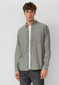 Overhemd met lange mouwen en knopen in grijze stof met een subtiel patroon, voorzien van een borstzak en een button-down kraag. Gedragen over een wit T-shirt.
