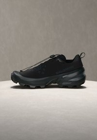 Μαύρο παπούτσι trail running Salomon με ανθεκτική σόλα, σύστημα γρήγορου δέσιμου και ταινία έλξης σε ουδέτερο φόντο.