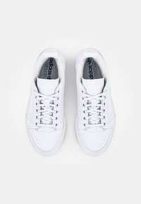 Zapatillas deportivas de cuero blanco con diseño de caña baja, punta redonda, cordones en la parte frontal, acentos perforados y marca negra en la plantilla.