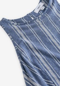 Robe bleue sans manches avec des rayures verticales blanches et un col rond, posée à plat montrant la zone de la poitrine et des épaules.