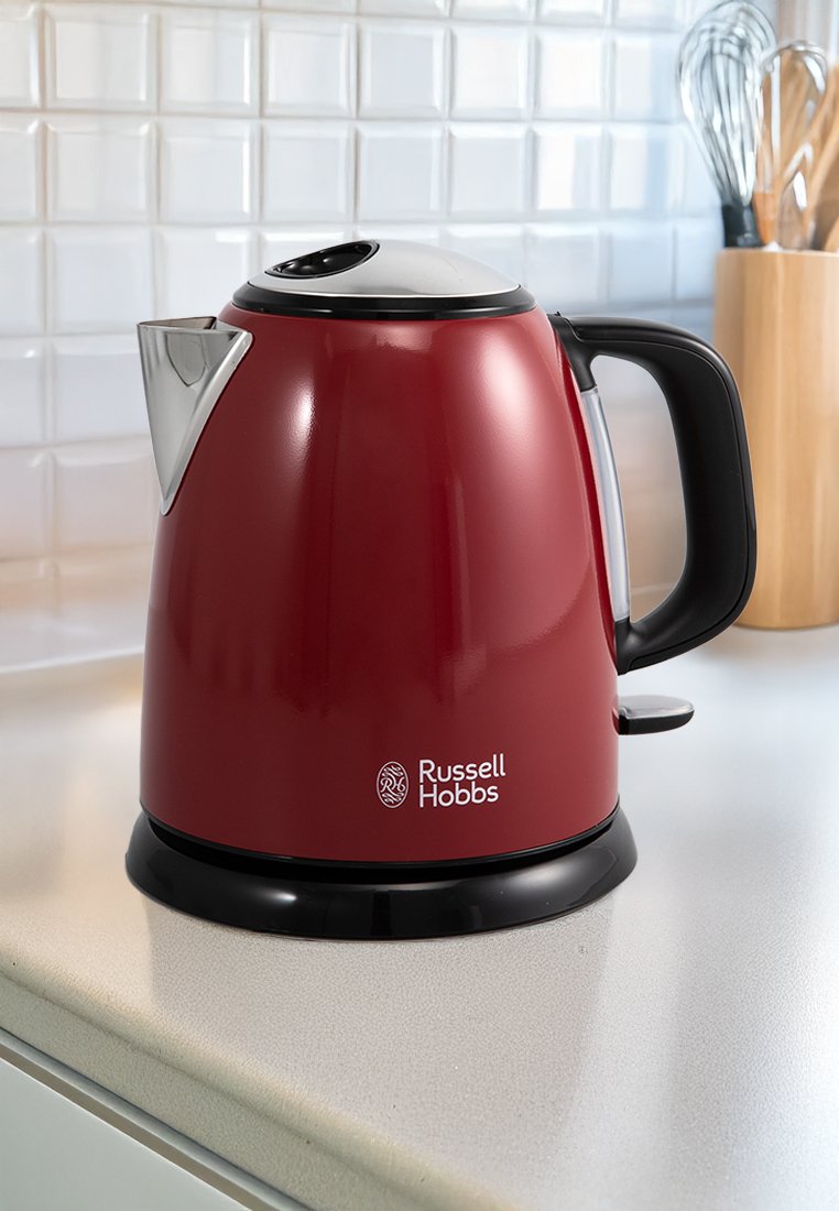 Czerwany czajnik elektryczny o błyszczącej powierzchni, czarnej podstawie i stalowym dzióbku. Posiada uchwyt oraz wyraźnie widoczny logo Russell Hobbs.