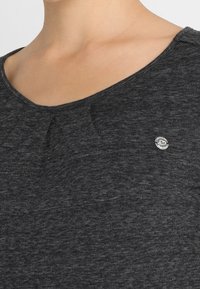 Czarny melanzowany t-shirt z okrągłym dekoltem, krótkimi rękawami i małym okrągłym logo na górnej lewej stronie klatki piersiowej.
