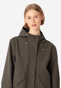 Chaqueta marrón con capucha, que presenta una textura suave, dos bolsillos frontales y cordones ajustables para un ajuste personalizable.