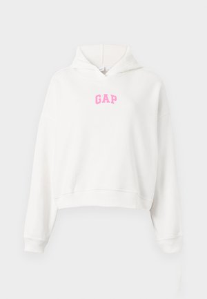 Valkoinen lyhyt huppari, jossa vaaleanpunainen "GAP"-logo rinnassa, pitkät hihat ja edessä huppu, yksinkertaisella taustalla.