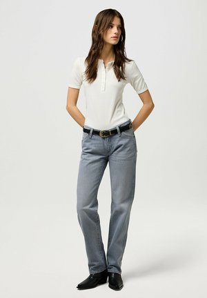 Hvid ribbet kortærmet polo shirt med knaplukning, parret med lyseblå lige ben jeans og et sort bælte. Sorte spidse støvler.