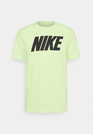 Jasnozielona koszulka z krótkim rękawem i okrągłym dekoltem z wyraźnym czarnym napisem „NIKE” na piersi, przedstawiona na jednolitym tle.