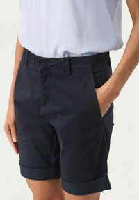 Marinblå skräddarsydda shorts med upprullade fållar, tillverkade av lättviktsmaterial. Har framfickor och en platt midja.
