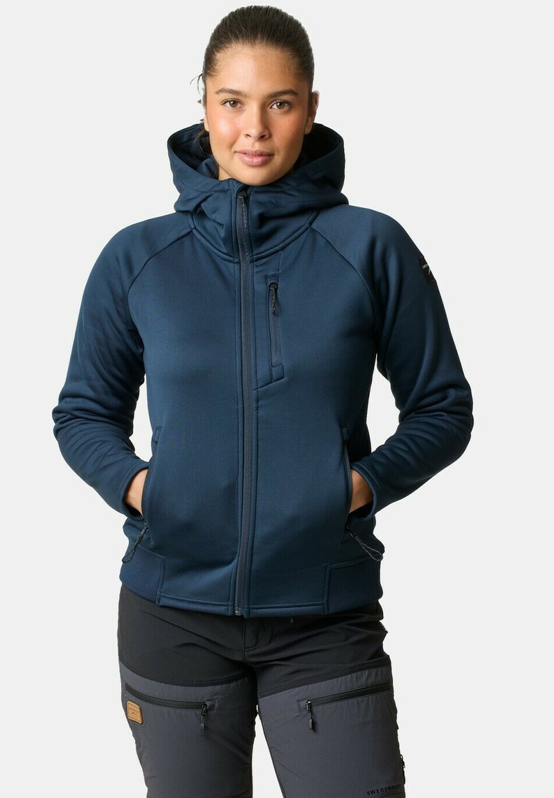 Marineblauwe fleece jack met capuchon, voorrits en zakken. Kenmerkend is de gladde textuur en atletische pasvorm, met contrasterende stofaccenten.