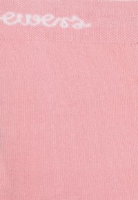 Rosa bomullssokker med ribbestruktur og en hvit logo øverst. Materialet ser mykt og elastisk ut.