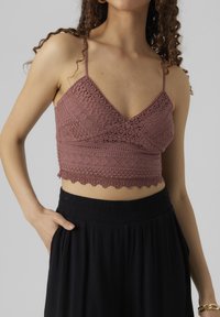 Mauve színű horgolt bralette V-nyakkivágással, állítható pántokkal, fodros szegéllyel, texturált mintázattal, fekete magas derekú nadrággal párosítva.