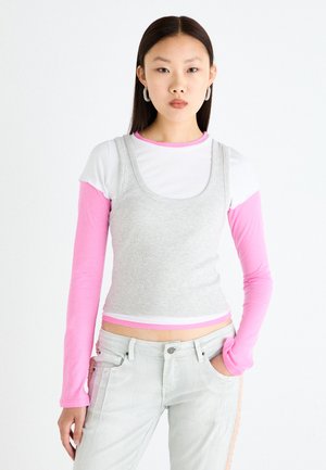 Layered top featuring a gray ribbed tank over a white crew neck shirt with pink long sleeves. Includes light gray jeans with side accents.
