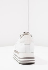 Baskets blanches avec un talon en daim texturé, des accents de rayures grises et une semelle épaisse. Conçues avec une forme arrondie et une finition lisse.