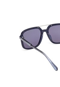 Sluneční brýle čtvercového rámu z tmavě modrého plastu s gradientními šedými skly a stříbrnými akcenty na můstku a stranicích.