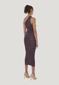 Gestricktes, figurbetontes, ärmelloses Kleid in Dunkellila mit horizontalen Cut-out-Mustern. Kombiniert mit hautfarbenen High Heels und texturiertem Stoff.