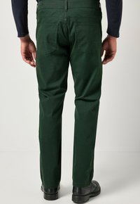 Groene katoenen broek met een rechte snit, voorzien van twee achterzakken en een soepele textuur. Draagt men met zwarte schoenen.