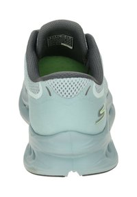 Light blue athletic shoe with a mesh upper, padded collar, and rubber sole. Features a logo detail on the back and green insole.