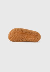 Semelle de chaussure en caoutchouc marron avec motifs antidérapants texturés et accents en relief, présentant un logo et une indication de taille sur le côté.