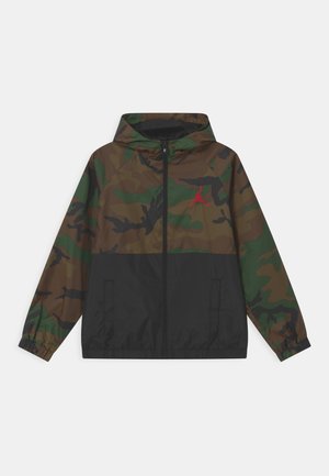 Camouflage jas met capuchon, met groene en bruine patronen. Zwarte onderste paneel en rode logo-accent. Elastische manchetten, volledige ritssluiting, lichtgewicht materiaal.