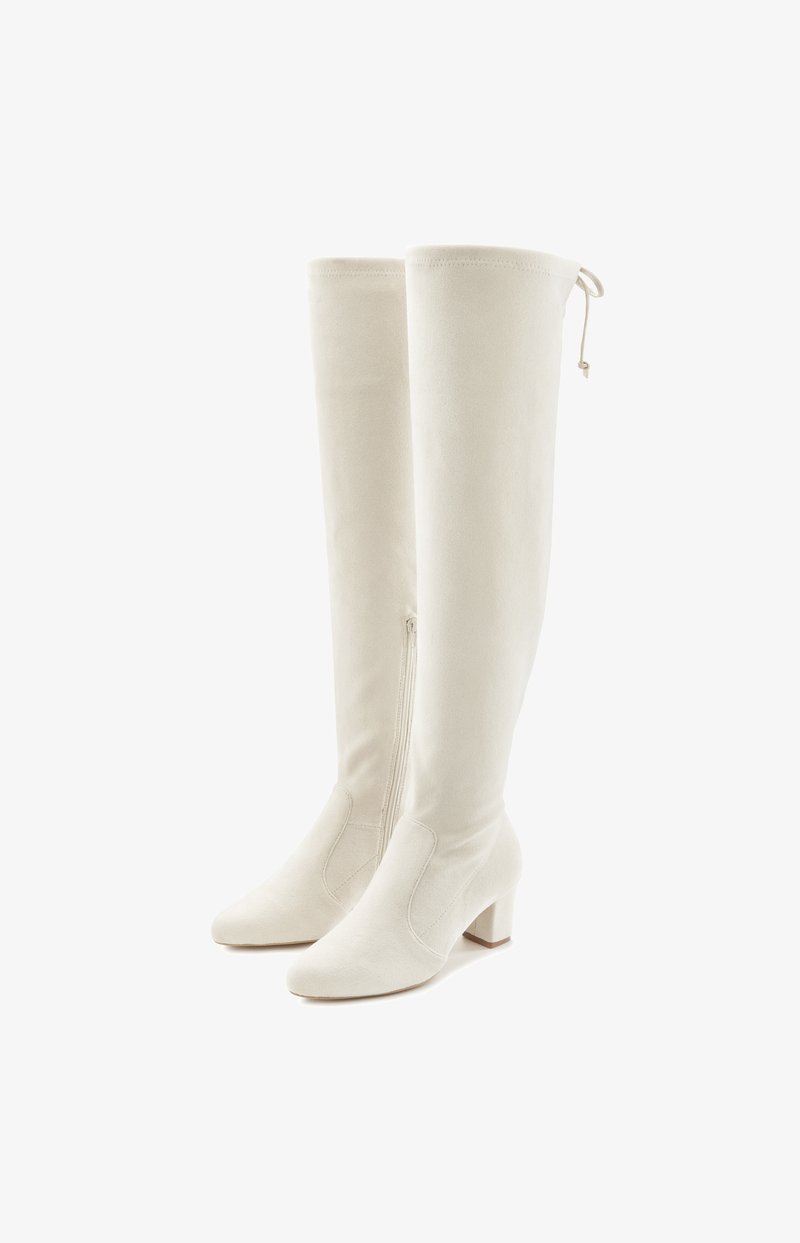 Knee-high valge sametnahast saapad, millel on sile tekstuur, terav nina ja plokknukk. Omab külgset tõmblukku ja ülemises osas nöörimist.