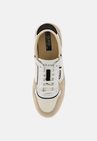 Sneaker bianco e beige con accenti neri, materiali testurizzati, punta rotonda, lacci piatti, logo del brand sulla linguetta e colletto imbottito.