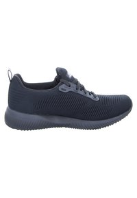 Schwarzer Sportschuh mit einem strukturierten Mesh-Obermaterial, Schnürdesign und einer gepolsterten Sohle mit einem geriffelten Muster für besseren Halt.