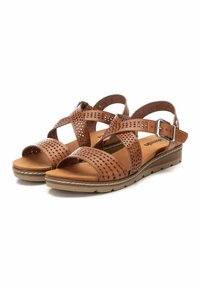 Sandali in pelle marrone con cinturini perforati, fibbia regolabile alla caviglia e soletta imbottita su una suola marrone chiaro.