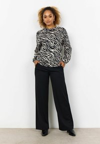 Black and beige zebra print long-sleeve top paired with black wide-leg pants and black shoes, set against a plain white background.