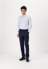 Lys blå stripe skjorte med spiss krage, kombinert med mørk marinebukser og svarte sko, med en skreddersydd passform og elegant design.