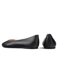 Bailarinas de cuero negro con punta redonda, textura suave, suela delgada y detalles de costura mínimos. Diseño elegante y estilizado.