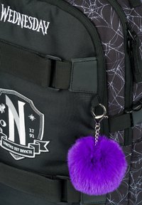 Černý látkový batoh s motivem pavučiny, bílým výšivkou, nášivkou s erbem a odnímatelným klíčenkou ve tvaru fialového kožíšku.